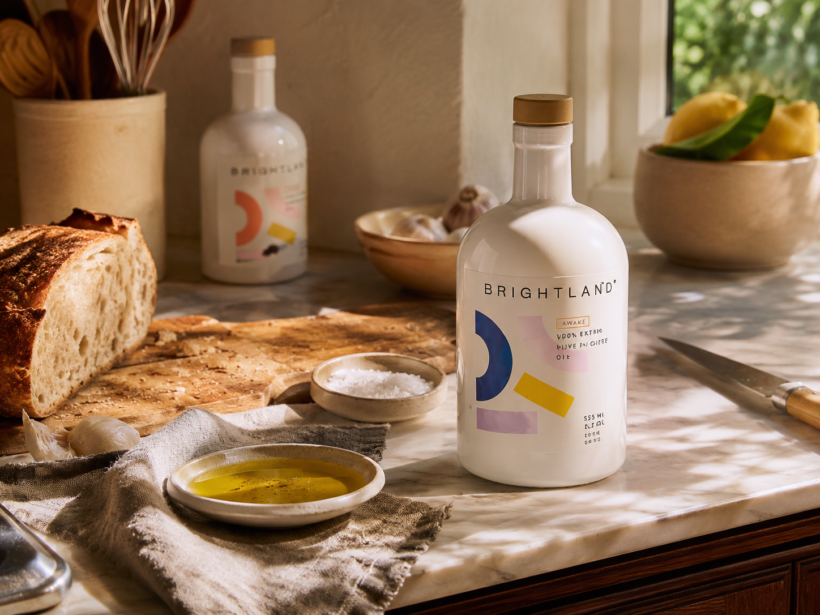 Brightland extra virgin olive oil in a lived-in kitchen with bread, garlic and everyday cooking essentials